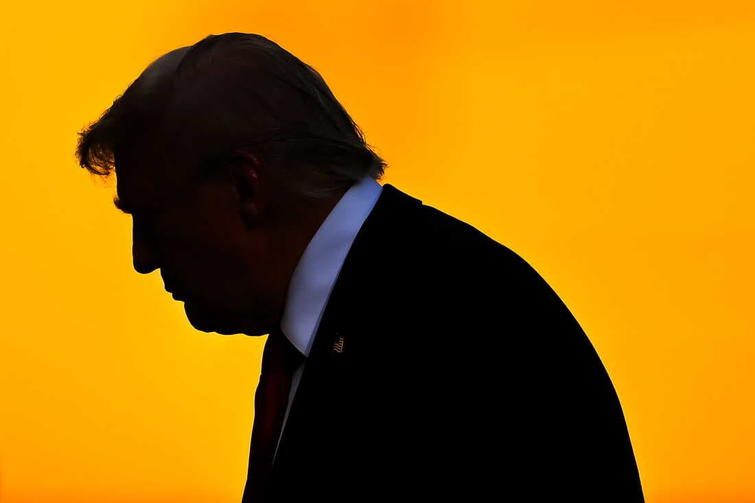 This photo shows a dark silhouette profile of President Trump on July 13 at MetLife Stadium in East Rutherford, New Jersey. The background is a marigold orange color.