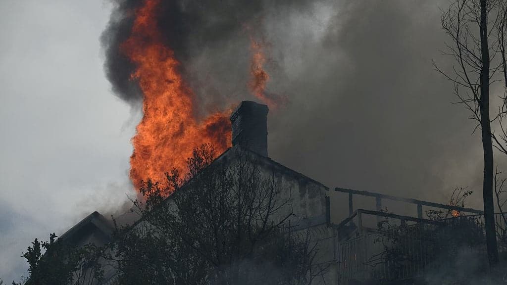 Flames from the Norte Fire are seen above a building in San Juan Capistrano, Calif.